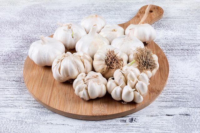 Bunches of garlic on cutting board high angle view on a light wo